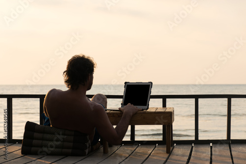 Fotomural Digital nomad working online on the beach and seeing beautiful sunset