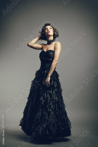 Fotografia  Jeune femme en robe de soirée regarde vers le haut, la main derrière la tête