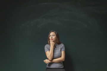 Thoughtful young woman on chalkboard background