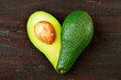 Fresh avocado in the shape of a heart isolated on wood table background. Love symbol made of fruit. Exotic fruit.