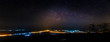Panorama of Milky way over city lights, long exposure photograph with grain