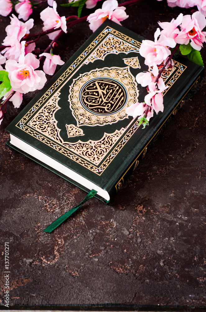 Islamic Book Koran And Spring Flowers Brunch On Dark Background With Arabic Calligraphy That Means The Holy Quran Sring Concept Selective Focus Wall Mural Tanchy25