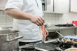 Koch legt Schinken in Pfanne auf dem Herd in einer Hotel oder Restaurant Küche