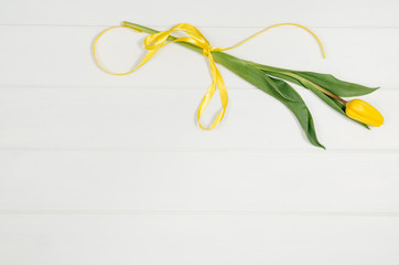 Poster - Background with yellow tulips on white wooden table top view. Creative woman's workspace concept with copy space. Product photograph taken from above with frame composition