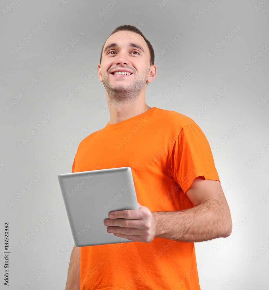 Handsome man with tablet computer on light background