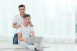 © Africa Studio - Happy gay couple sitting on floor with laptop against window