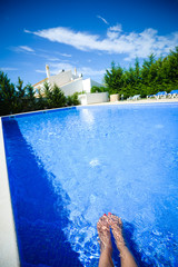 Woman legs inside open air swimming pool blue surface background