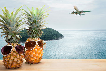 pineapple with sunglasses on tropical sea and airplane background,concept summer and travel background.