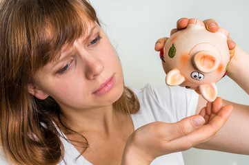 Unhappy woman shaking an empty piggy bank