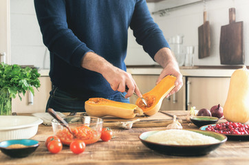 Man cooking a butternut squash  on a wooden table