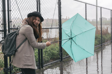 asian woman holding flipped umbrella while raining