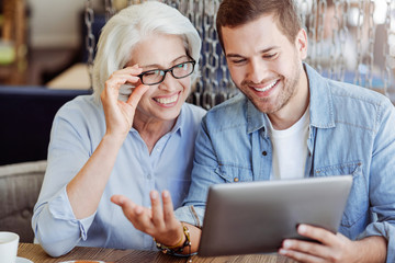 Positive aged woman and her grandson using tablet