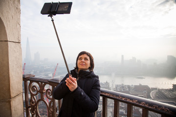 woman taking a selfie from the rooftop of St Paul's Cathedral on a foggy day in London - city break - tourism concept