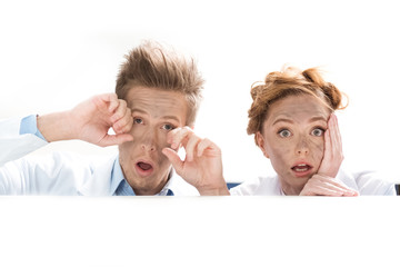 portrait of shocked scientists looking out behind table after experiment on white