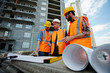 Low angle portrait of two workmen showing apartment building blueprints to inspector on construction site