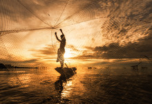 Silhouette Fisherman Fishing Nets On The Boat.