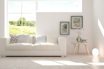 White room with sofa and green landscape in window. Scandinavian interior design