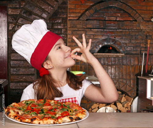 Zdjęcie XXL szczęśliwa mała dziewczynka gotuje z pizzą i ok ręką podpisuje wewnątrz pizzeria