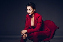 Attractive Business Woman. Portrait Of A Sexy Young Business Lady In A Red Suit On A Dark Background