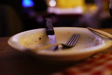 A dirty plate with a knife and a fork on it.