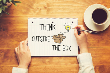 Think Outside The Box text with a person holding a pen