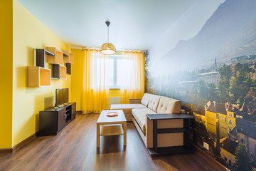 The interior of the living room in orange tones with a coffee table, TV and sofa