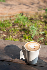 hot coffee in the morning on wood table with blurred garden in background