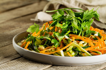 Canvas Print - Fresh Tasty Vegetable Vegetarian or Vegan Grated Salad with Carrot Zucchini Parsley Sesam and Chickpeas on Plate on Wooden Table