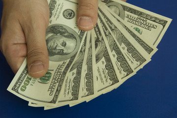 Man's hands holding dollars on dark blue background