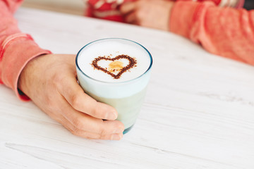 Wall Mural - White table with hands holding coffee with heart