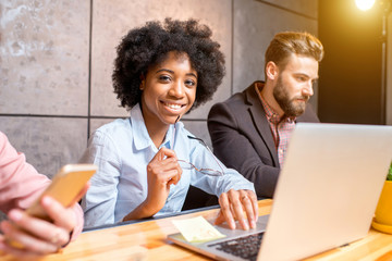 Beautiful african woman with handsome caucasian man working with laptop at the modern office interior