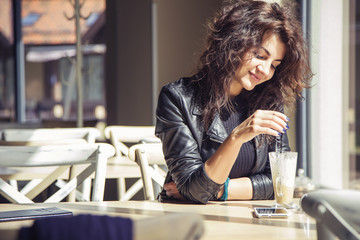 Brunette beautiful stylish caucasian woman in casual outfit on a walk on european city street sitting at the cafe waiting. copy space