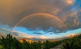 Fototapeta Tęcza - Evening rainbow in the sky over the city at sunset in the summer, in the rain