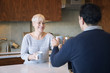 © Cavan Images - Smiling woman giving mug to man while sitting at table in home