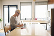 © Cavan Images - Senior woman using laptop computer at kitchen table in home
