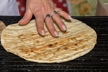 Woman's hand touching tortilla at barbecue grid