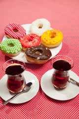 Wall Mural - Colorful donuts and two cups of tea on a red table