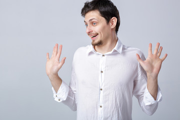 young attractive smiling brunette man in white shirt on gray bac