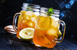 Black ice tea with lemon in a glass jar on a dark background, selective focus