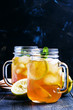 Black ice tea with lemon in a glass jar on a dark background, selective focus