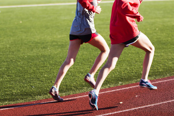 Two girls running together on a track