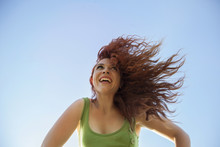 Cheerful Woman Feeling The Freedom On Her Curly Red Hair Isolated On A Blue Sky