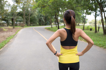 Wall Mural - Back view of young fitness woman running on the road in the morning, People and sport concept, Selective focus