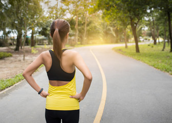 Wall Mural - Back view of young fitness woman running on the road in the morning. People and sport concept