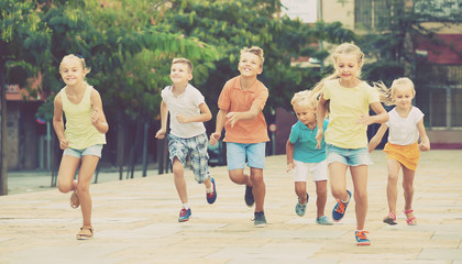 Wall Mural - Group of smiling children running together in town on summer