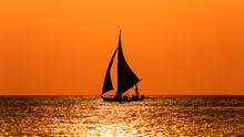 Sailing Boat Silhouette Against An Orange Sunset Sky