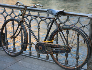 Wall Mural - black old bike leaning on the bridge above the river