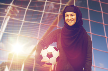 happy muslim woman in hijab over football goal