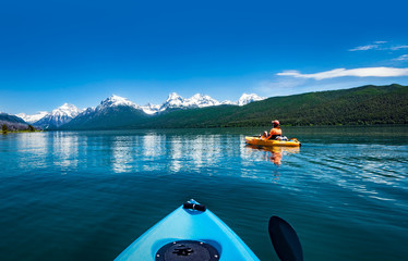 Wall Mural -  Kayaking in the spring by snow covered mountains on Lake McDonald in Glacier National Park Montana