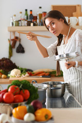 Wall Mural - Cooking woman in kitchen with wooden spoon